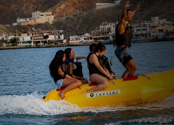 Grupo con chalecos salvavidas sobre una banana inflable remolcada en el mar