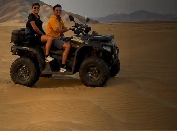 Dos personas en una cuatrimoto sobre la arena del desierto