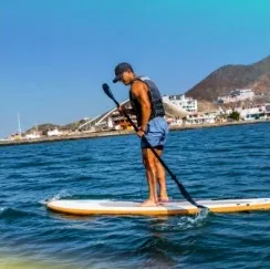 Hombre remando de pie sobre una tabla de paddle en el mar