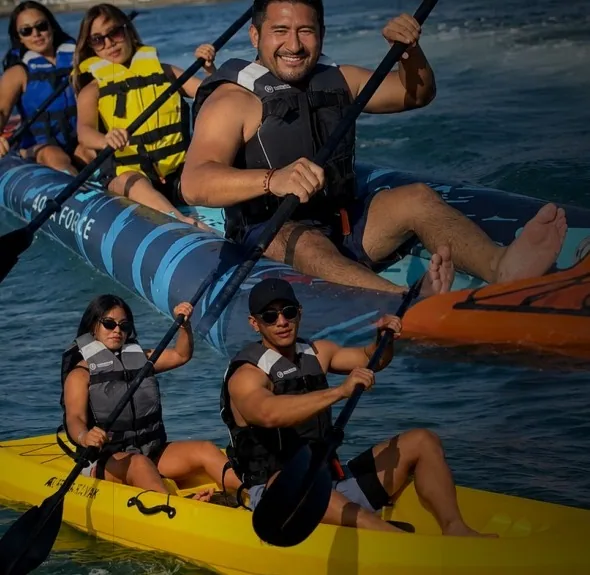 Grupo con chalecos salvavidas remando en kayaks dobles y triples
