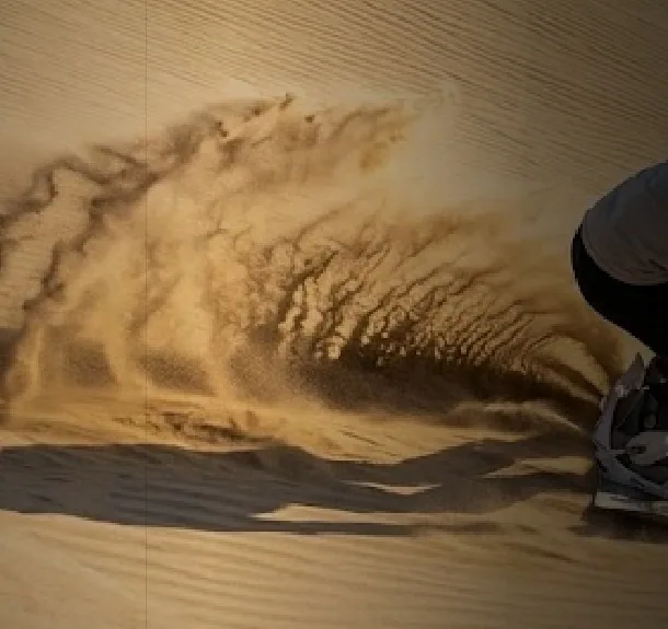 Tabla de sandboard levantando arena al bajar una duna