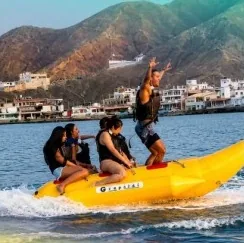 Personas celebrando sobre una banana inflable en el mar