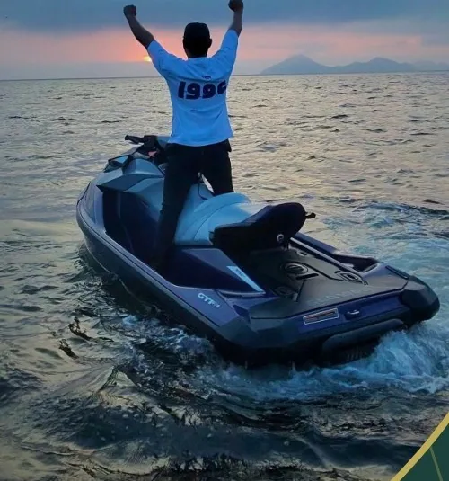 Persona de pie sobre una moto acuática en el mar al atardecer