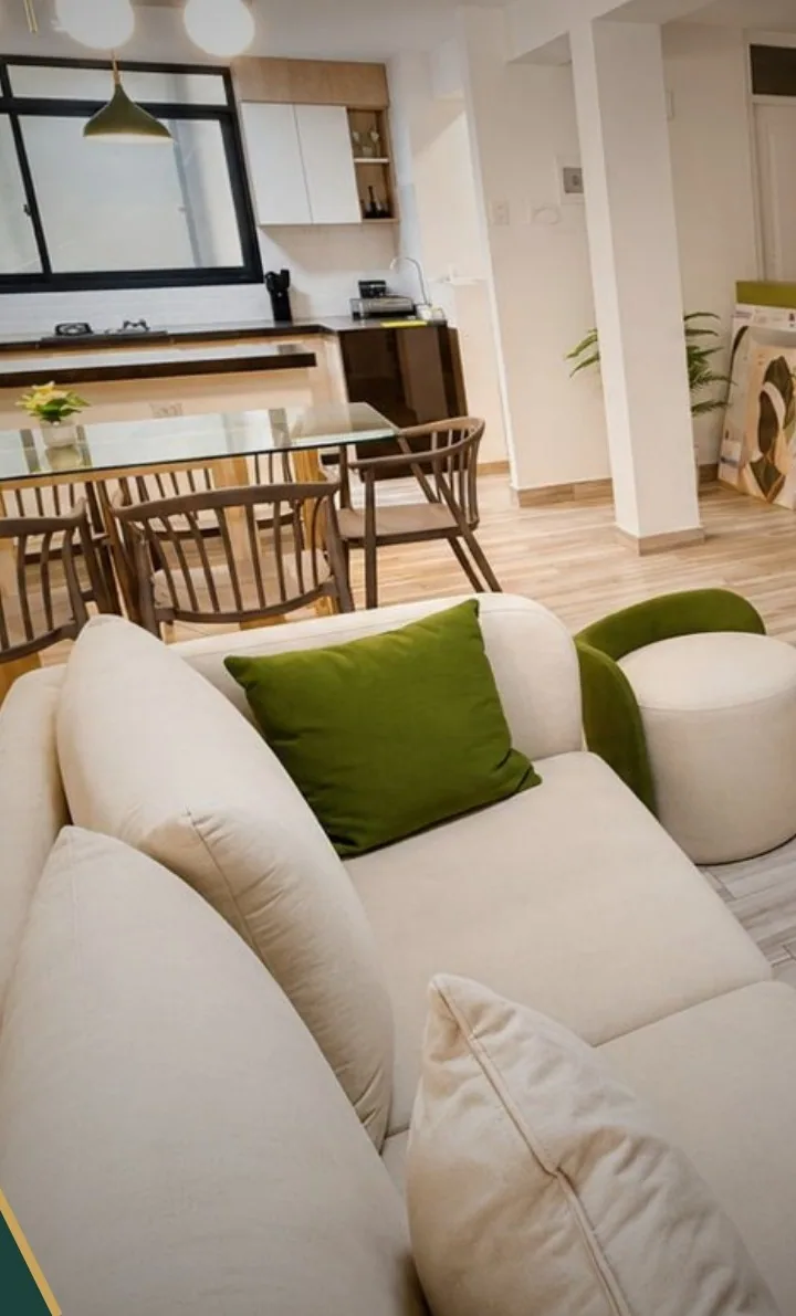 Sala con sofá blanco integrada al comedor y la cocina de un departamento