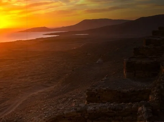 Atardecer sobre los cerros y los muros de piedra de un sitio arqueológico de Casma