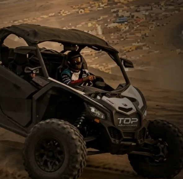 Piloto con casco en un UTV todo terreno sobre la arena