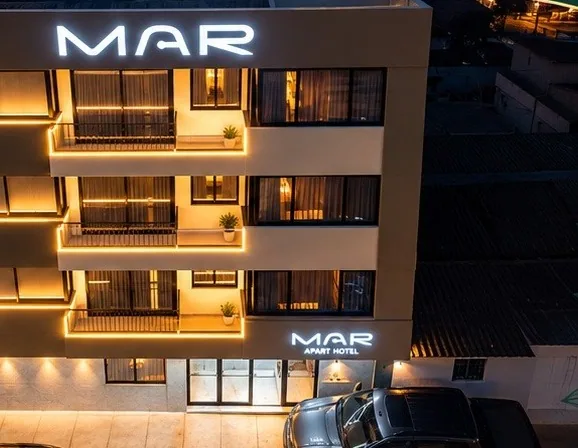 Fachada de MAR Apart Hotel iluminada de noche
